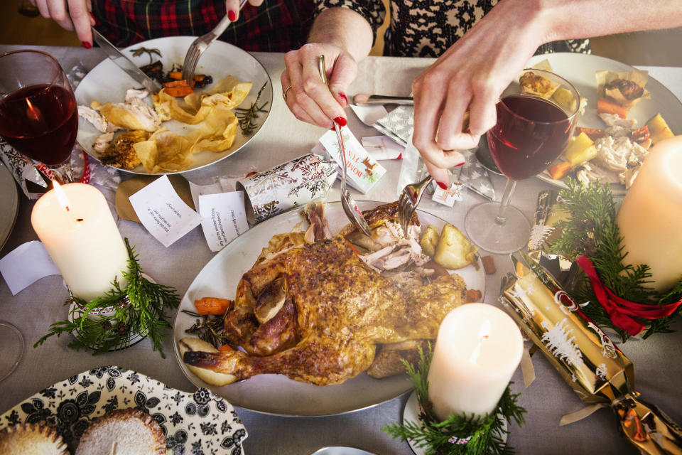 A woman's hands are seen cutting a turkey at Christmas dinner. 