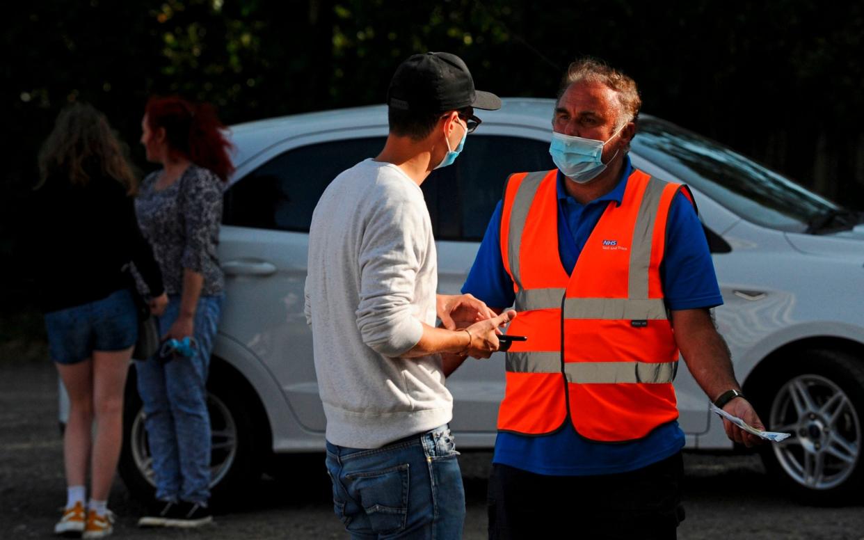 An employee of the NHS Test and Trace programme talks to a man who arrived with an appointment to get a test at a Covid-19 testing site after they had closed down the site for the day in Catford, southeast London -  DANIEL SORABJI / AFP