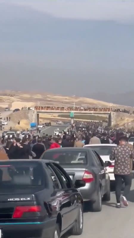 People march down the highway toward the Aychi Cemetery where Mahsa Amini is buried, near Saqez