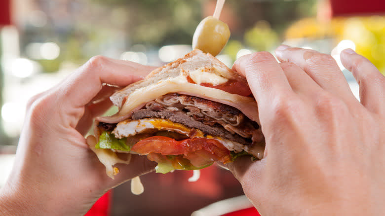 Person holding chivito sandwich