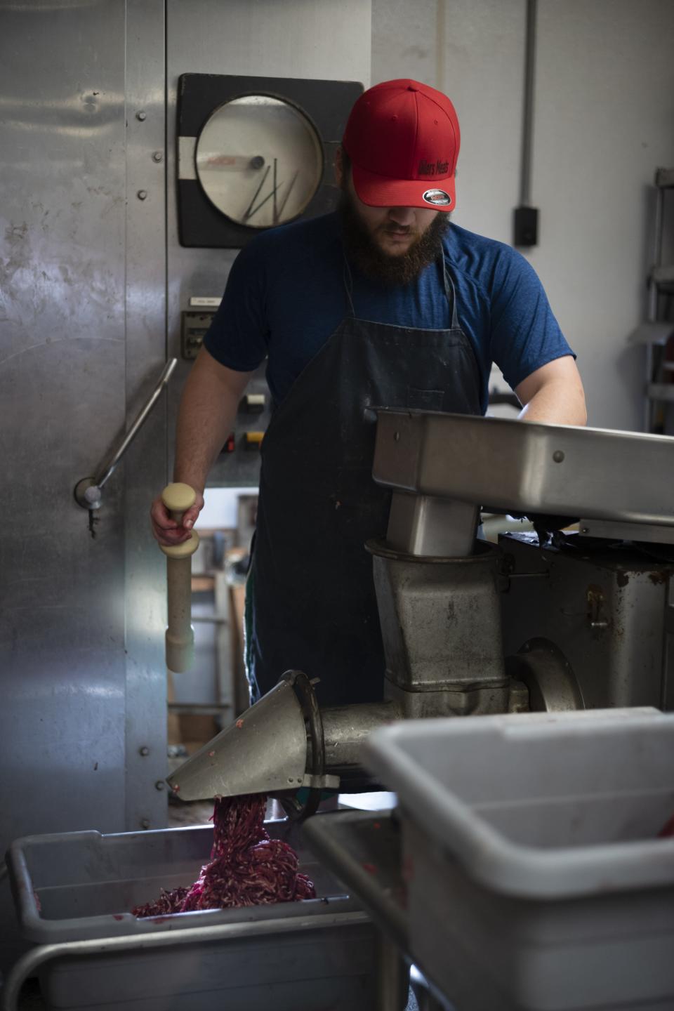 Hunter Hawkins grinds venison while processing deer at Oiler Meat Processing in Utica.