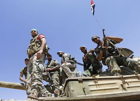 Syrian army fighters stand guard in the Qara area, in Syria's Qalamoun region, as members of the Islamic State (IS) group and their families are transported to Deir Ezzor under part of an unprecedented deal to end three years of jihadist presence on August 28, 2017 - Credit:  LOUAI BESHARA/ AFP