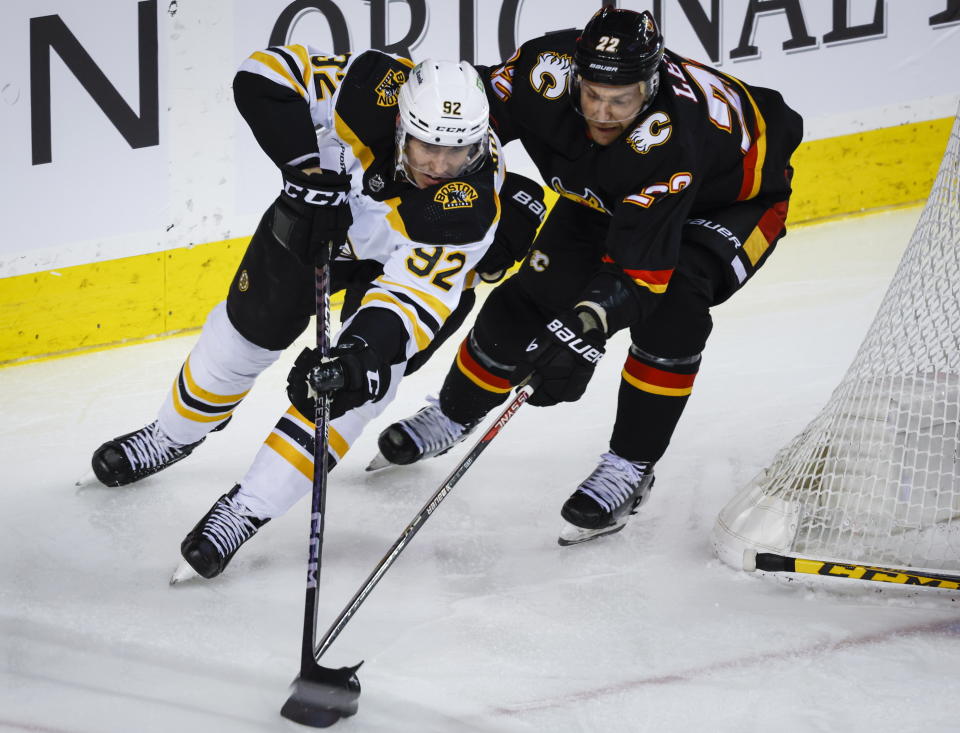 Boston Bruins forward Tomas Nosek, left, is checked by Calgary Flames forward Trevor Lewis during the second period of an NHL hockey game Tuesday, Feb. 28, 2023, in Calgary, Alberta. (Jeff McIntosh/The Canadian Press via AP)