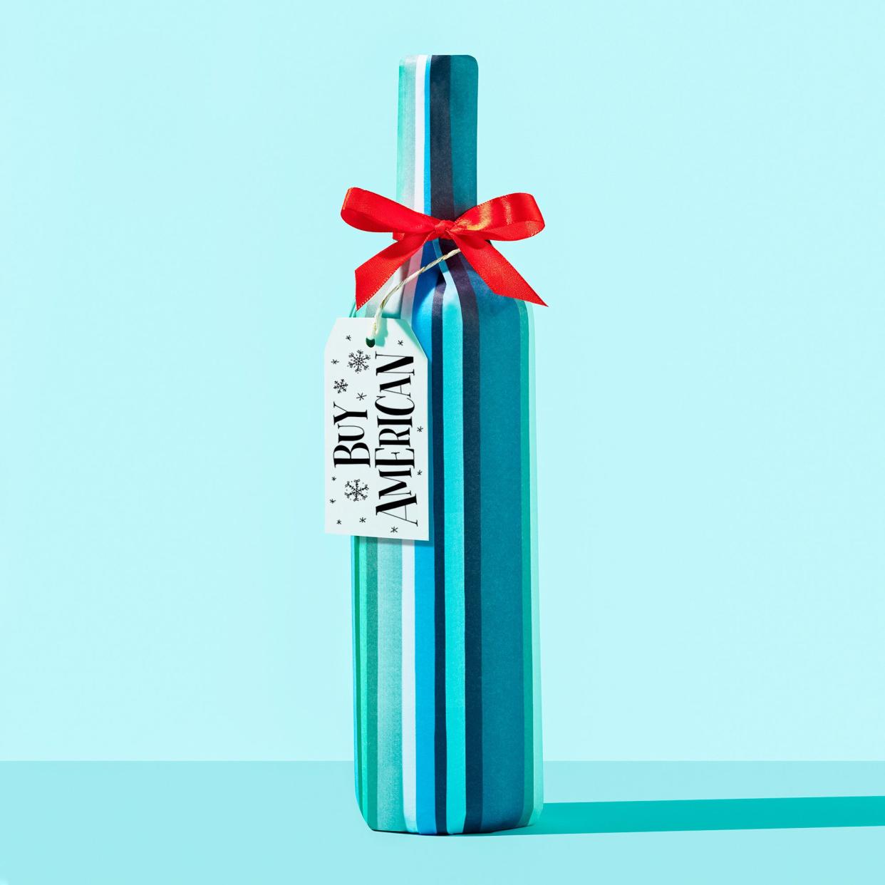 wrapped wine bottle on blue background with gift tag that reads, 