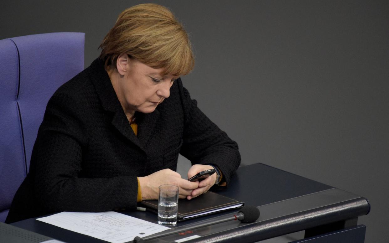 (FILES) In this file photo taken on December 16, 2015 German Chancellor Angela Merkel uses her mobile phone during a session of the Bundestag in Berlin on December 16, 2015. - The US spied on top politicians in Europe, including German Chancellor Angela Merkel, from 2012 to 2014 with the help of Danish intelligence, Danish and European media reported on Sunday. Danish public broadcaster Danmarks Radio (DR) said the US National Security Agency (NSA) had eavesdropped on Danish internet cables to spy on top politicians and high-ranking officials in Germany, Sweden, Norway and France. (Photo by ODD ANDERSEN / AFP) (Photo by ODD ANDERSEN/AFP via Getty Images) - ODD ANDERSEN/ AFP