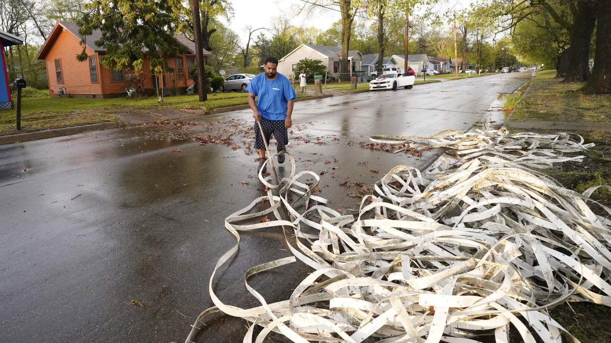 An area resident sweeps up tennis lines blown off the courts at the Battlefield Tennis Center in Jackson, Miss., by the strong winds from a severe weather outbreak in the state, Wednesday, March 30, 2022. (AP Photo/Rogelio V. Solis)