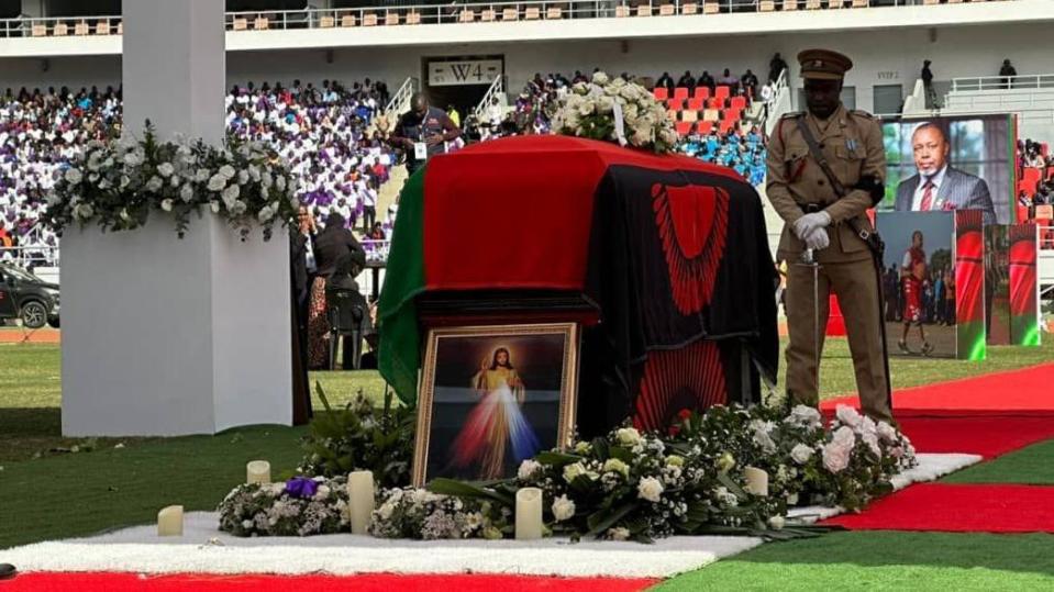 A coffin draped with Malawi's flag with a guard of honour looking on