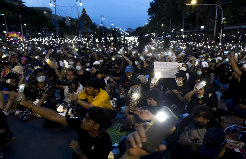 Pro-democracy activities display mobile phones with flash lights on during a protest at Democracy Monument in Bangkok, Thailand, Sunday, Aug, 16, 2020. Protesters have stepped up pressure on the government demanding to dissolve the parliament, hold new elections, amend the constitution and end intimidation of the government's opponents. (AP Photo/Gemunu Amarasinghe)