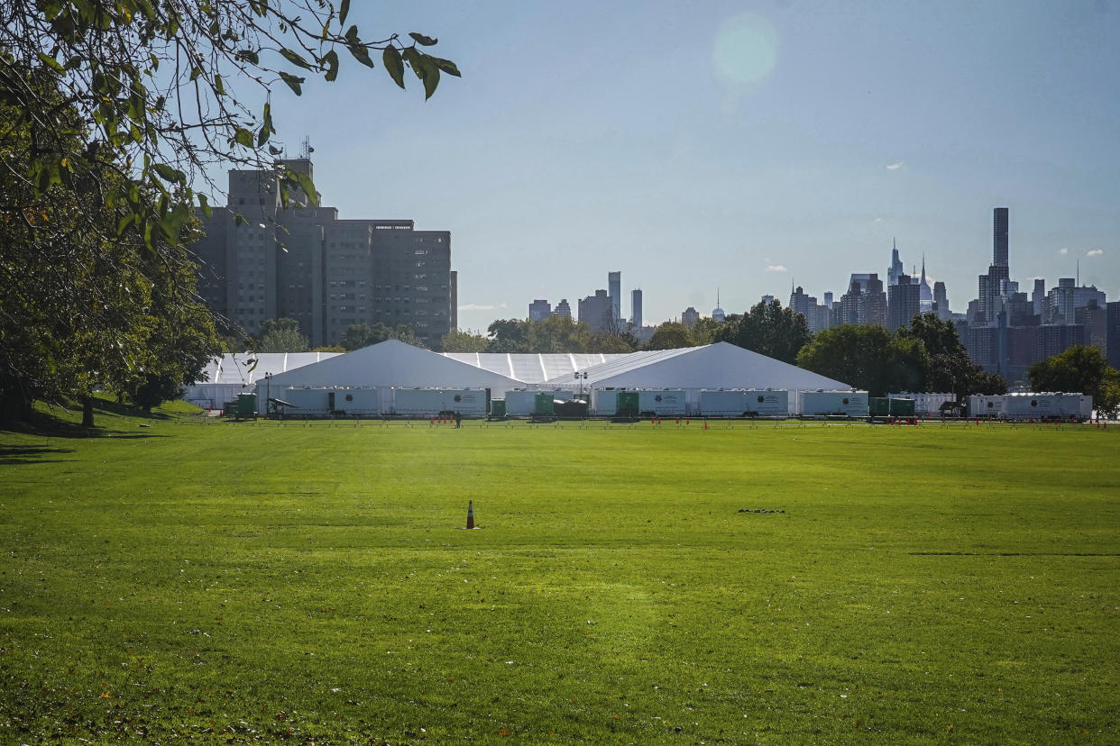 Randall's Island Humanitarian Emergency Response and Relief Center, center, a complex of giant tents, is New York City's latest temporary shelter for an influx of international migrants being bused into the city by southern border states, Oct. 18, 2022, in New York. The shelter will start taking in single adult men on Wednesday, Oct. 19, with facilities including laundry, regular meals and access to international calls. (AP Photo/Bebeto Matthews)