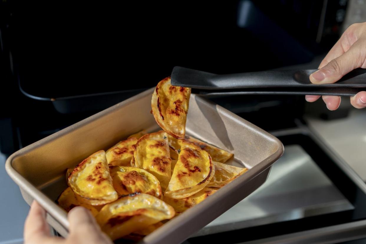 Baked dumplings in pan man putting them in oven