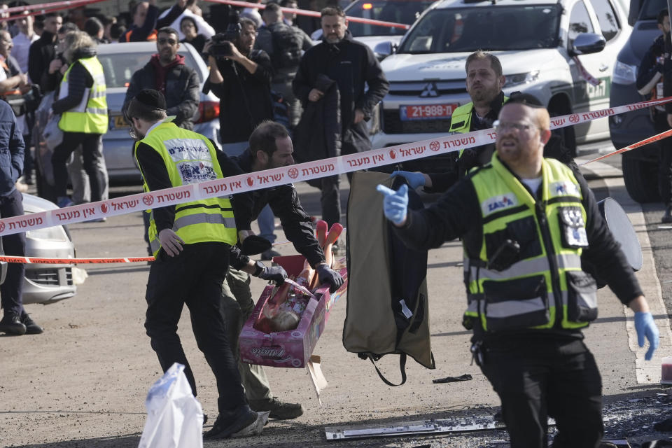 Members of Zaka Rescue and Recovery team and Israeli police forensics pick up a doll at the site of a car-ramming attack at a bus stop in Ramot, a Jewish settlement in east Jerusalem, Friday, Feb. 10, 2023. A driver plowed a car into a crowded bus stop in east Jerusalem on Friday, killing two people, including a six-year-old, and injuring five others before being shot and killed, Israeli police and medics said, the latest escalation as violence grips the contested capital. (AP Photo/Mahmoud Illean)