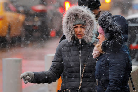 Pedestrians walk down the sidewalk as snow falls in the Times Square neighborhood of New York, U.S., February 12, 2019. REUTERS/Lucas Jackson
