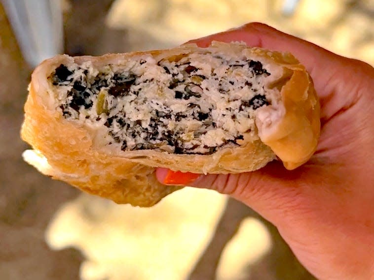 hand holding a spinach empanada from cafe tola