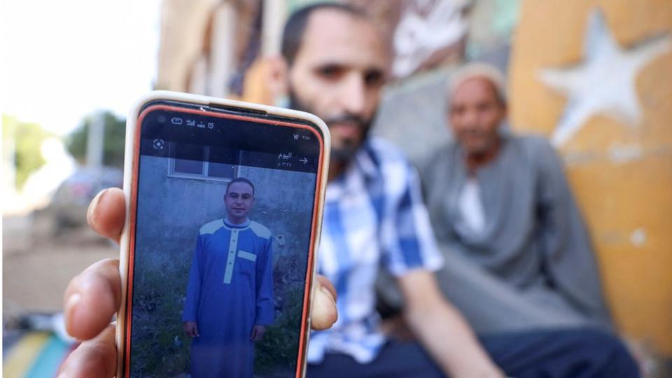 A man shows a photo of his brother Aly, who died along with his three cousins in Libya after Storm Daniel hit the country