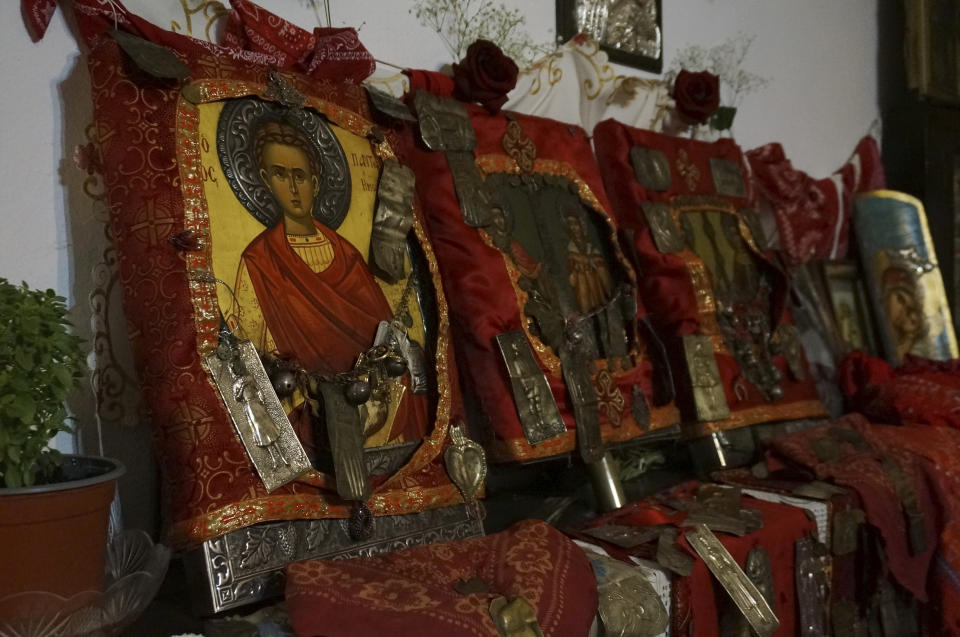 Icons of Orthodox saints framed in red cloth hung with votive offerings are venerated in a special room called "konaki" in the village of Lagkadas, Greece, on Monday, May 22, 2023. Devotees of St. Constantine celebrate his feast day with elaborate rituals that include dancing with these icons over a bed of burning coals. (AP Photo/Giovanna Dell'Orto)