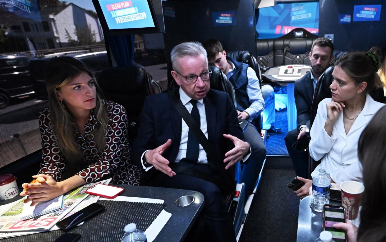 Michael Gove, the Levelling Up Secretary, is pictured this morning talking to journalists on the Conservative Party's general election campaign battle bus