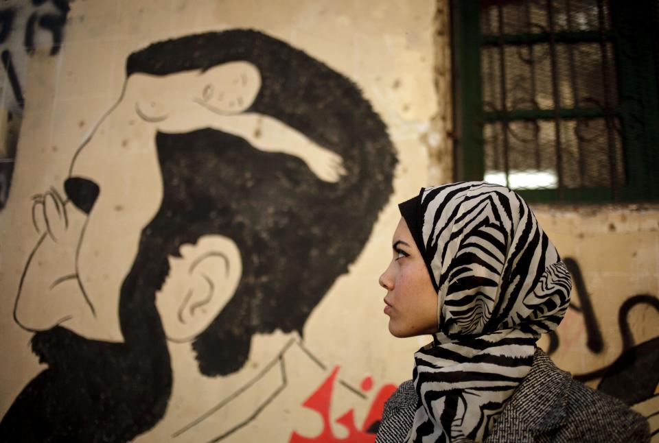 FILE - In this Tuesday, Dec. 10, 2013 file photo, Egyptian rapper Myam Mahmoud poses for a portrait next to a mural in downtown Cairo. Mahmoud, an 18-year-old Egyptian, rapped her way to the semi-finals of the Middle East’s hit TV show “Arabs Got Talent.” While she didn’t win the program, Mahmoud did succeed in throwing a spotlight on something more than just herself. On a very public stage, her songs pulled back the curtain on the slew of challenges that women across the Arab world are fighting to overcome. (AP Photo/Maya Alleruzzo, File)