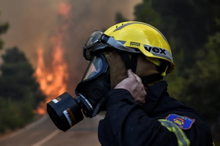 A firefighter adjusts his mask as a wildfire burns at the village of Kontodespoti, on the island of Evia