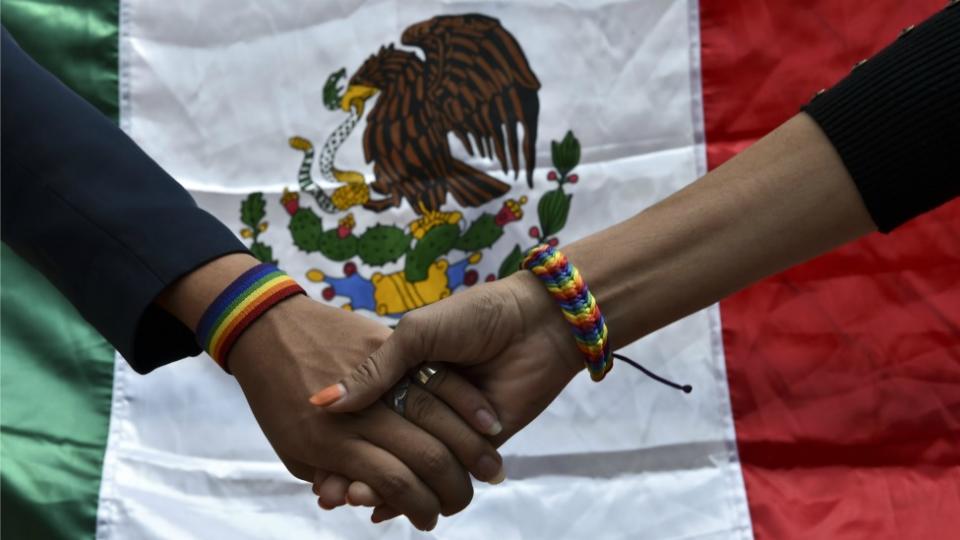 Manos entrelazadas con una bandera mexicana.