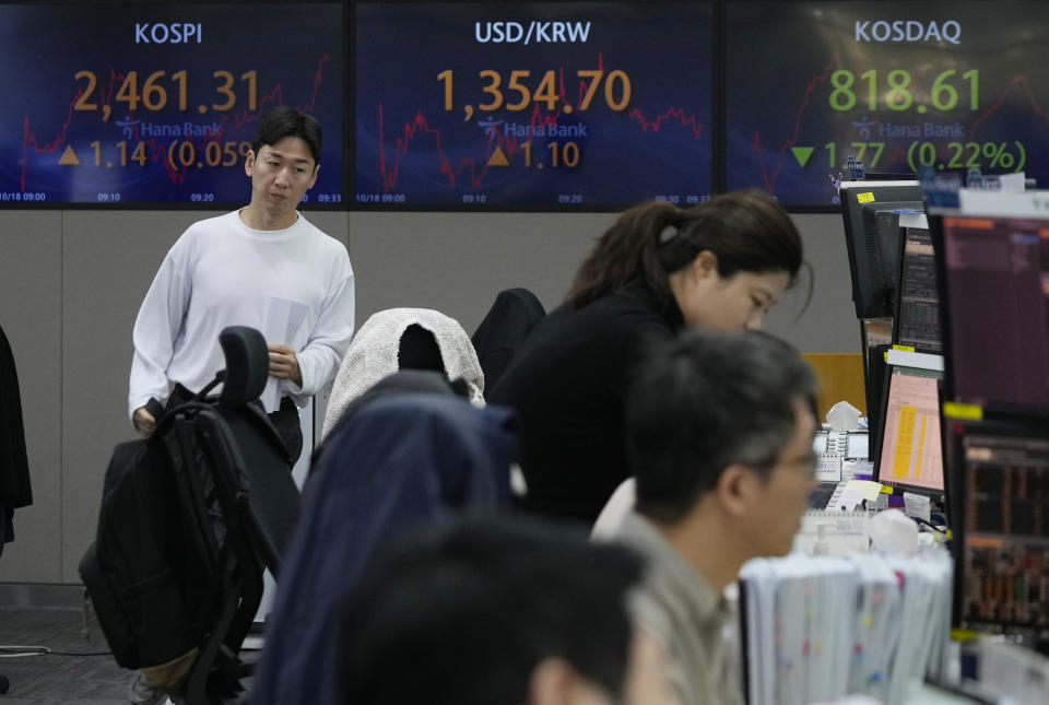 A currency trader passes by the screens showing the Korea Composite Stock Price Index (KOSPI), left, and the foreign exchange rate between U.S. dollar and South Korean won, center, at the foreign exchange dealing room of the KEB Hana Bank headquarters in Seoul, South Korea, Wednesday, Oct. 18, 2023. (AP Photo/Ahn Young-joon)