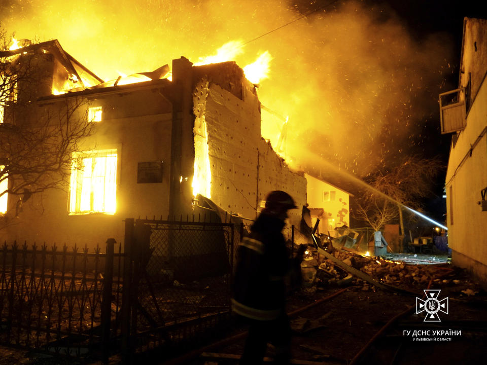 In this photo provided by the Ukrainian Emergency Service, firefighters work on the site of a burning building after a Russian drone attack in Dublyany, Lviv region, Ukraine, Monday, Jan. 1, 2024. (Ukrainian Emergency Service via AP)