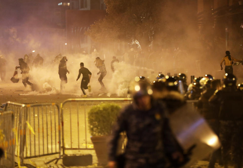 Anti-government protesters run away as the riot police fired tear gas against them during a protest in downtown Beirut, Lebanon, Saturday, Dec. 14, 2019. The recent clashes marked some of the worst in the capital since demonstrations began two months ago. The rise in tensions comes as politicians have failed to agree on forming a new government. (AP Photo/Hussein Malla)