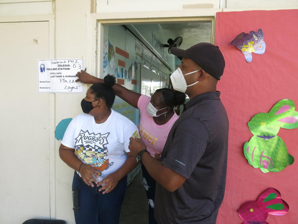 A volunteer points out that a voter is in the wrong line and asks him to go to a neighboring classroom to cast his ballot in Loíza, Puerto Rico, Sunday, Aug. 16, 2020. Thousands of Puerto Ricans on Sunday got a second chance to vote for the first time, a week after delayed and missing ballots marred the original primaries in a blow to the U.S. territory’s democracy. (AP Photo/Dánica Coto)