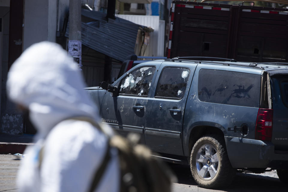 A forensics investigator walks the scene of a massive shootout in Parangaricutiro, Mexico,Thursday, March 10, 2022. Authorities in the avocado-growing zone of western Mexico said five suspected drug cartel gunmen have been killed in a massive firefight between gangs. ( AP Photo/Armando Solis)