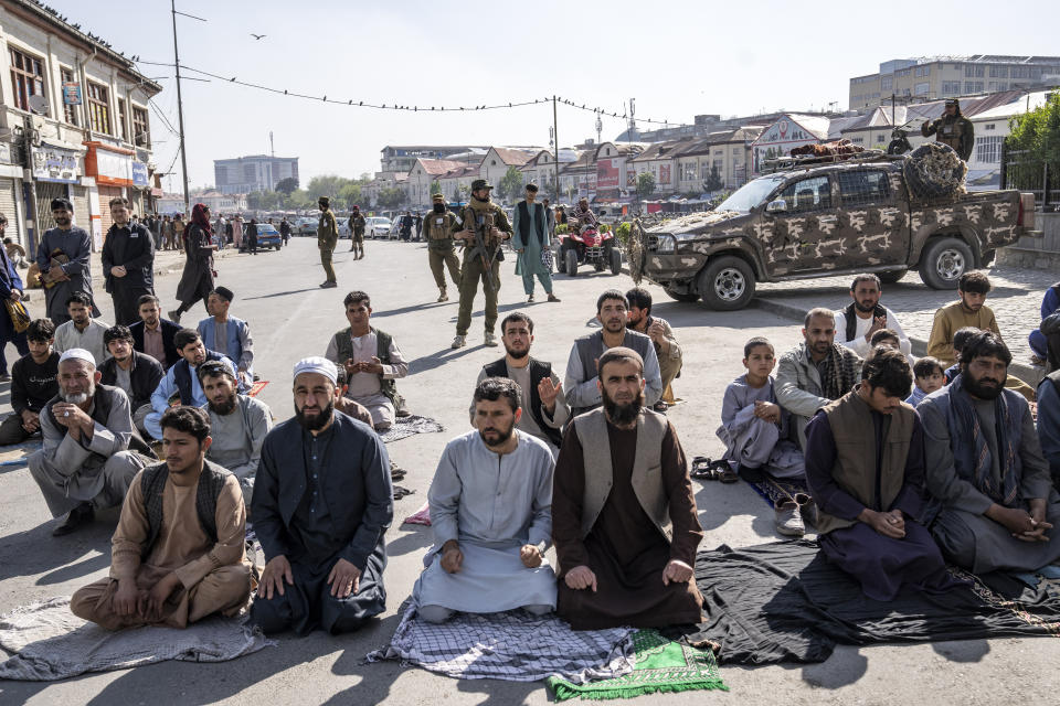 Taliban fighters stand guard as Afghan people attend Eid al-Fitr prayers, marking the end of the holy fasting month of Ramadan, in Kabul, Afghanistan, Friday, April 21, 2023. (AP Photo/Ebrahim Noroozi)