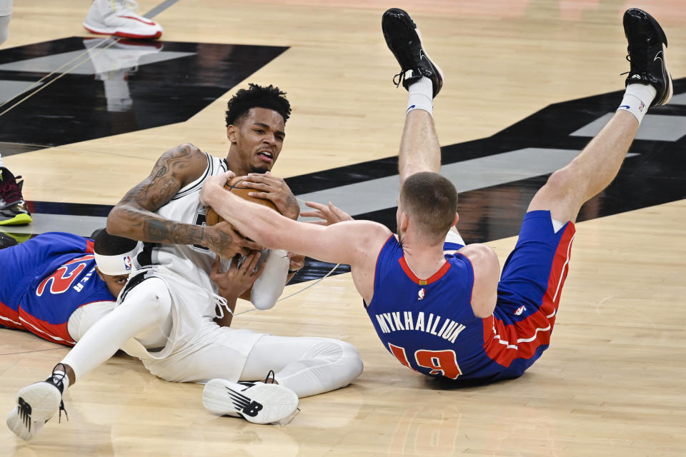 San Antonio Spurs guard Dejounte Murray, center, fights for possession with Detroit Pistons' Svi Mykhailiuk, right, and Tim Frazier during the second half of an NBA basketball game Saturday, Dec. 28, 2019, in San Antonio. San Antonio won 136-109. (AP Photo/Darren Abate)