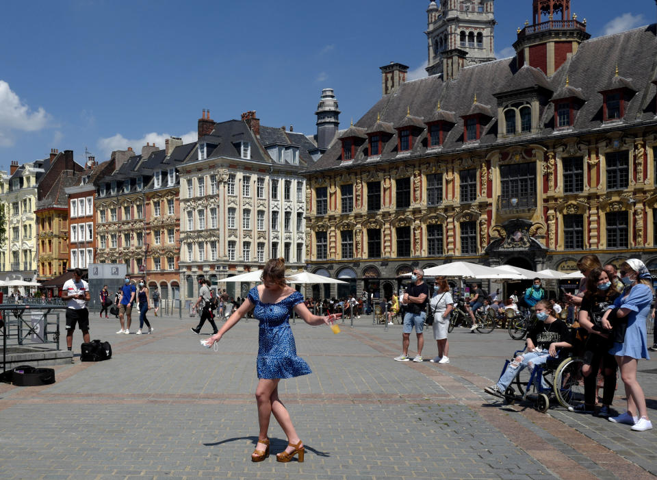 FILE - In this June 6, 2021, file photo, a woman dances by a cafe terrace in Lille, northern France. In France, authorities said it’s no longer always mandatory to wear masks outdoors and said they would end a nightly coronavirus curfew this weekend. (AP Photo/Michel Spingler, File)