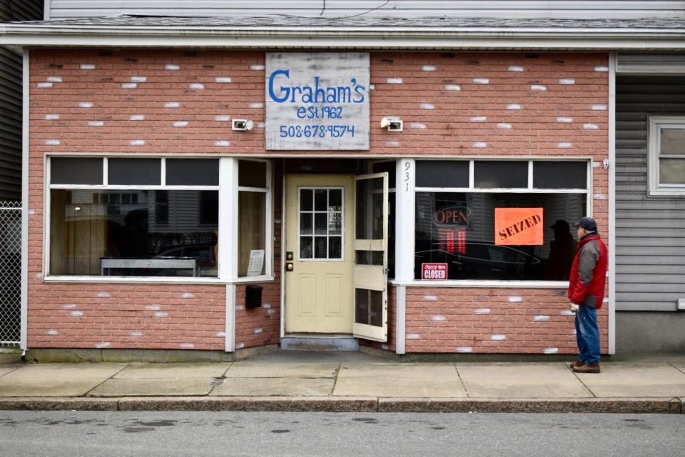 A passerby looks in the window at Graham's Hot Dogs at 931 Bedford St., in Fall River.