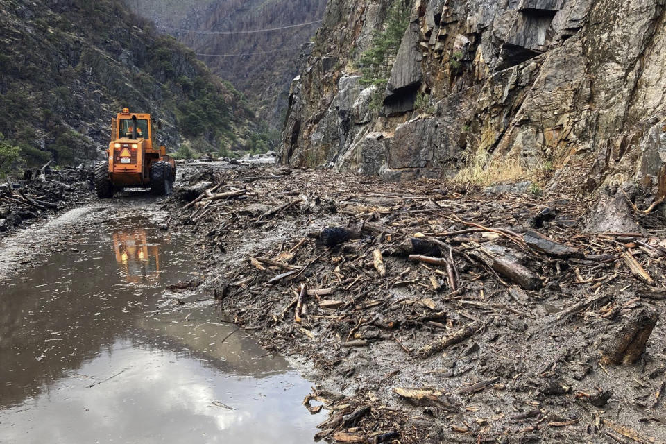 In this photo provided Caltrans, crews work to clear a multiple slides along Highway 70 in the Feather River Canyon near Belden, Calif., Sunday, June 12, 2022. A 50-mile (80-km) stretch of the highway was closed indefinitely on Monday after mud, boulders and dead trees inundated lanes during flash floods along a wildfire burn scar. There was no estimate for when the mountain route might reopen. (Caltrans via AP)