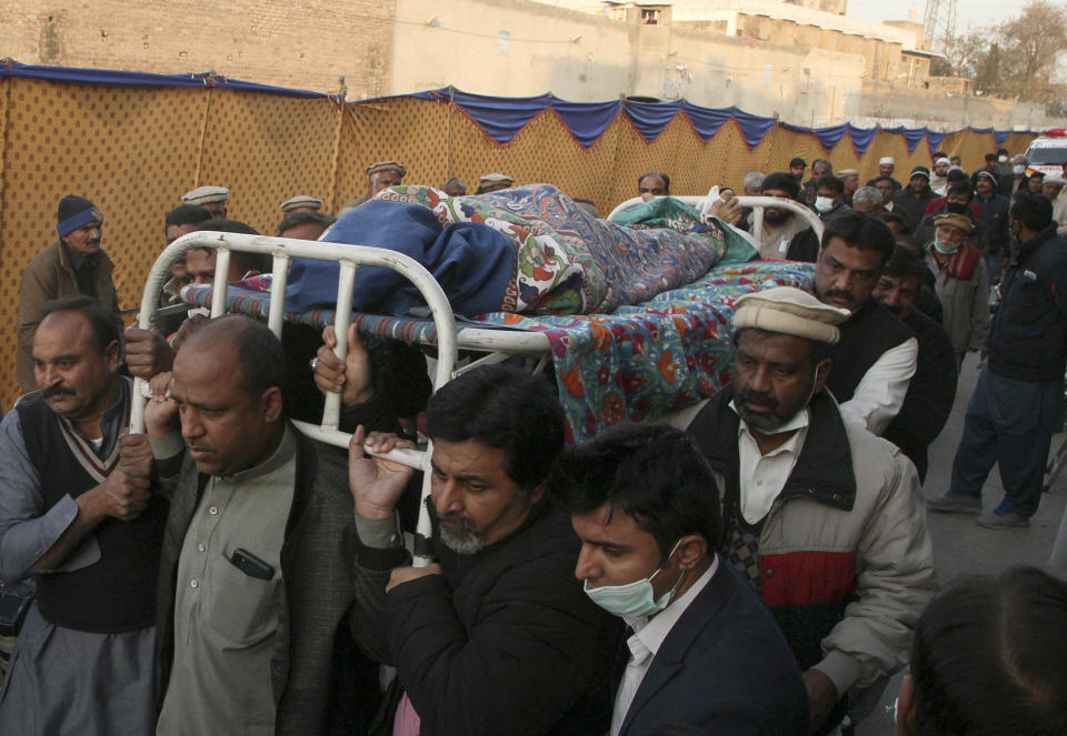 Pakistanis carry the body of Christian priest Father William Siraj, 75, who was killed by unknown gunmen, at his home in Peshawar, Pakistan, Sunday, Jan. 30, 2022. Police said gunmen killed Siraj and wounded another priest as they were driving home from Sunday Mass in Pakistan’s northwestern city of Peshawar. (AP Photo/Muhammad Sajjad)
