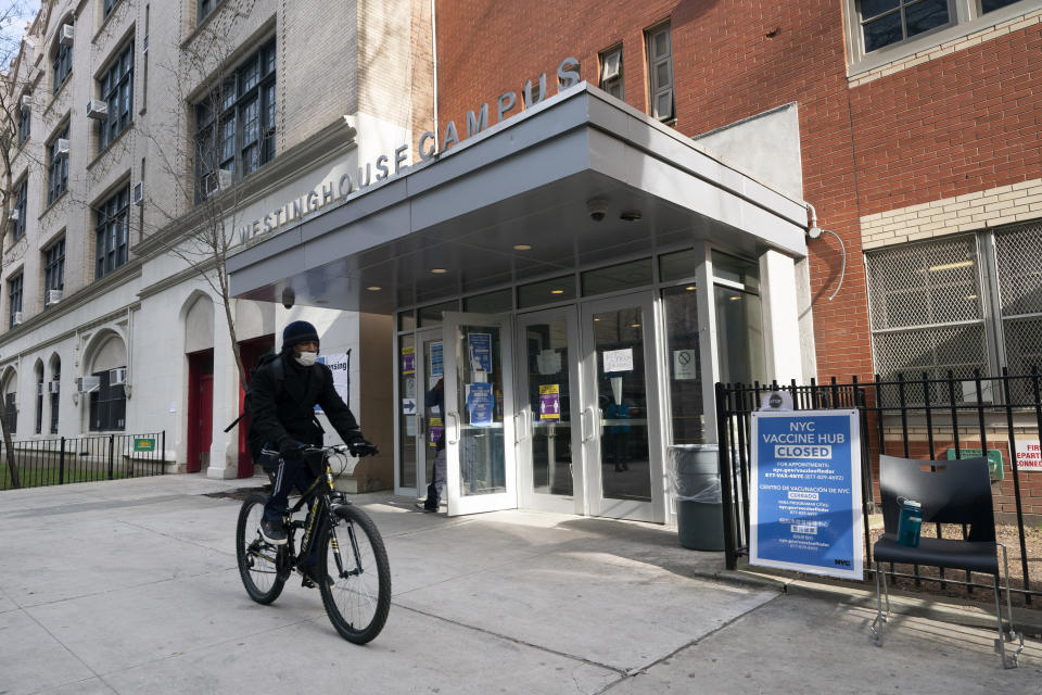 FILE - In this Jan. 21, 2021, file photo, a cyclist passes a closed vaccination center at the George Westinghouse High School in New York. An increasing number of COVID-19 vaccination sites around the U.S. are canceling appointments because of vaccine shortages in a rollout so rife with confusion and unexplained bottlenecks. (AP Photo/Mark Lennihan, File)