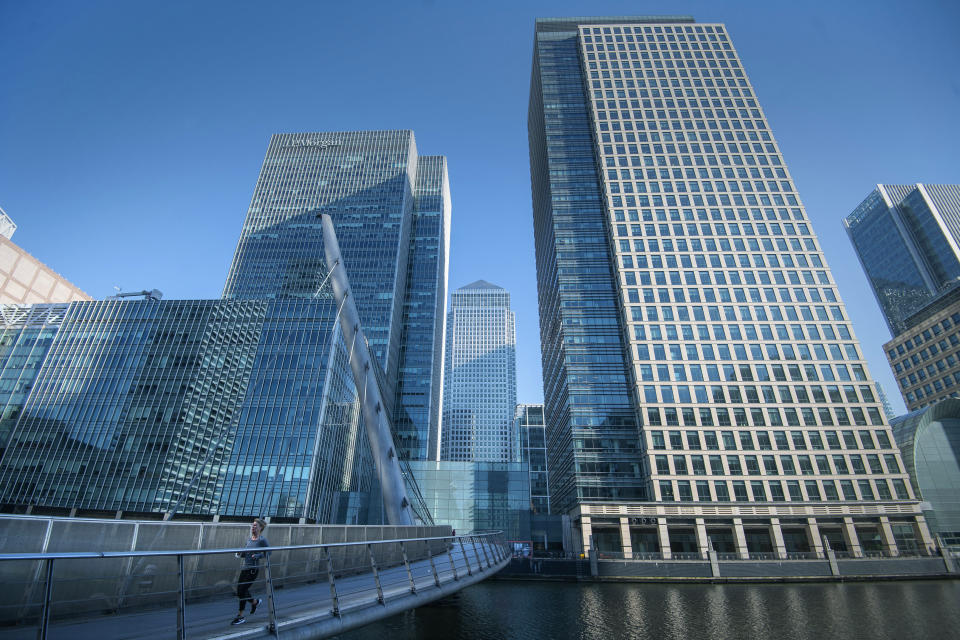 A woman runs in Canary Wharf, during rush hour,  in London, Wednesday March 25, 2020. For most people, the coronavirus causes mild or moderate symptoms, such as fever and cough that clear up in two to three weeks. (Victoria Jones/PA via AP)