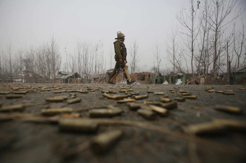 An Indian policeman walks past empty bullet cartridges lying on road near the site of a gun-battle in Mujagund area some 25 Kilometers (16 miles) from Srinagar, Indian controlled Kashmir, Sunday, Dec. 9, 2018. Indian troops killed three suspected rebels in the outskirts of disputed Kashmir's main city ending nearly 18-hour-long gunbattle, officials said Sunday. (AP Photo/Mukhtar Khan)