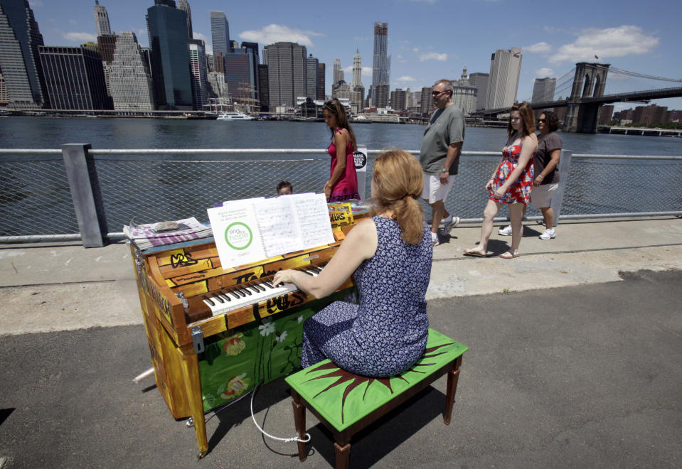 FILE - In this June 21, 2010 file photo, Carolyn Enger, of Englewood, N.J., plays a piano in Brooklyn Bridge Park, in the Brooklyn borough of New York. The piano was one of 60 that were part of the first year of Sing for Hope’s Pianos, a grassroots group of more than 1,000 artists who volunteer to make art accessible to everyone. (AP Photo/Richard Drew, File)