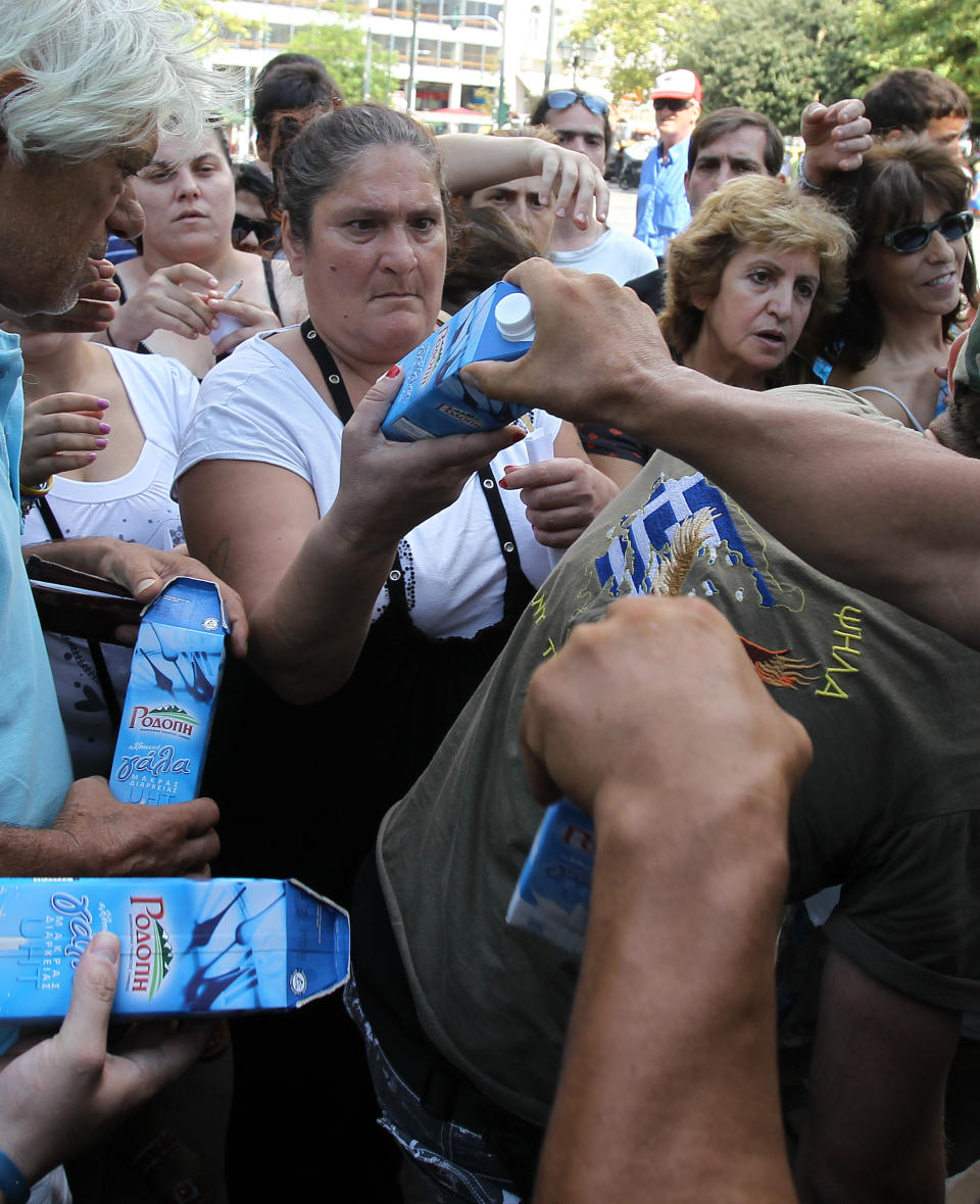 Members of Greece's extreme right Golden Dawn party hand out milk at Athens' main Syntagma Square, opposite parliament, on Wednesday, Aug. 1, 2012. The volunteers checked ID cards of the public before handing Greek citizens food that included milk cartons, pasta, potatoes and olive oil. Golden Dawn won 18 seats in the 300-seat parliament in June general elections. Senior party members openly support a policy of granting Greek citizenship based on racial identity. The party has stepped up its charity effort as Greece is suffering through a fifth year of recession, with rapidly rising rates of poverty and unemployment. (AP Photo/Thanassis Stavrakis)