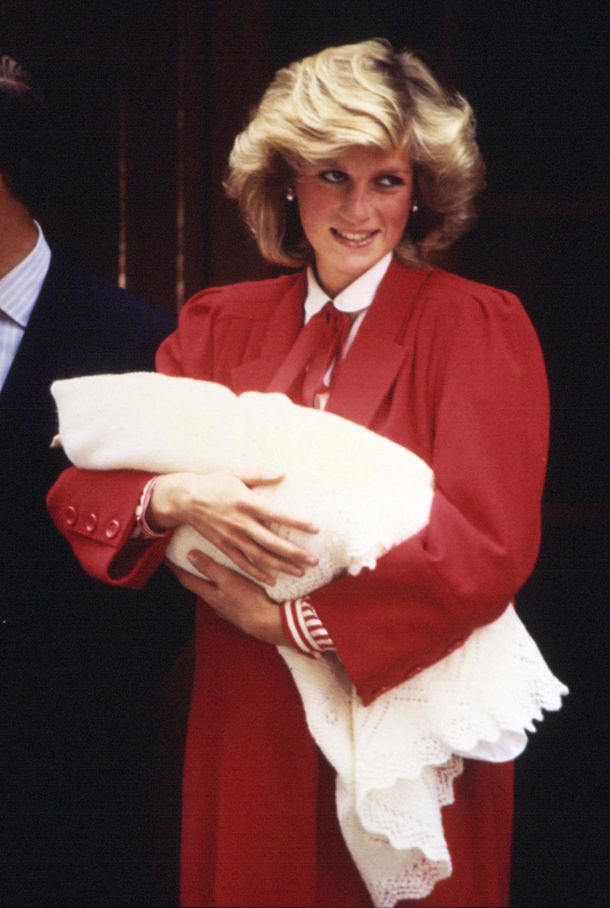 Diana holds newborn Prince Harry, wrapped in a shawl, in her arms as she leaves hospital after his birth in 1984