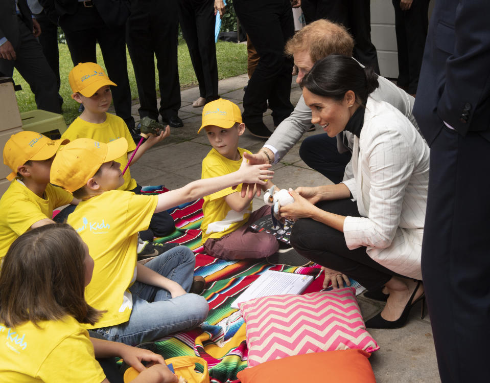 Britain's Prince Harry and his wife Meghan, the Duchess Sussex talk with school children as they attend a lunchtime reception hosted by Prime Minister Scott Morrison with Invictus Games competitors, their family and friends in the city's central parkland in Sydney on Sunday, Oct. 21, 2018. (Paul Edwards/Pool Photo via AP)