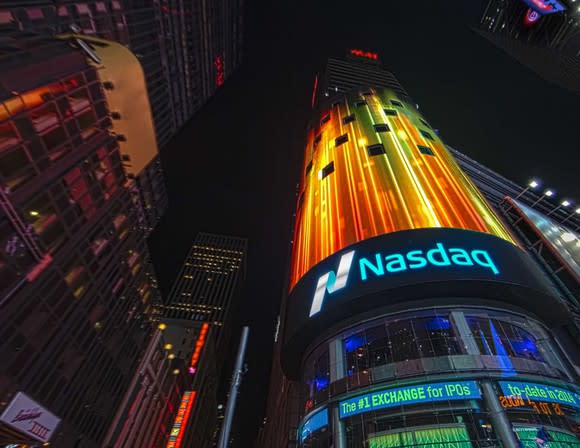 Nasdaq building in Times Square at night, with lights on the screen above the Nasdaq logo.