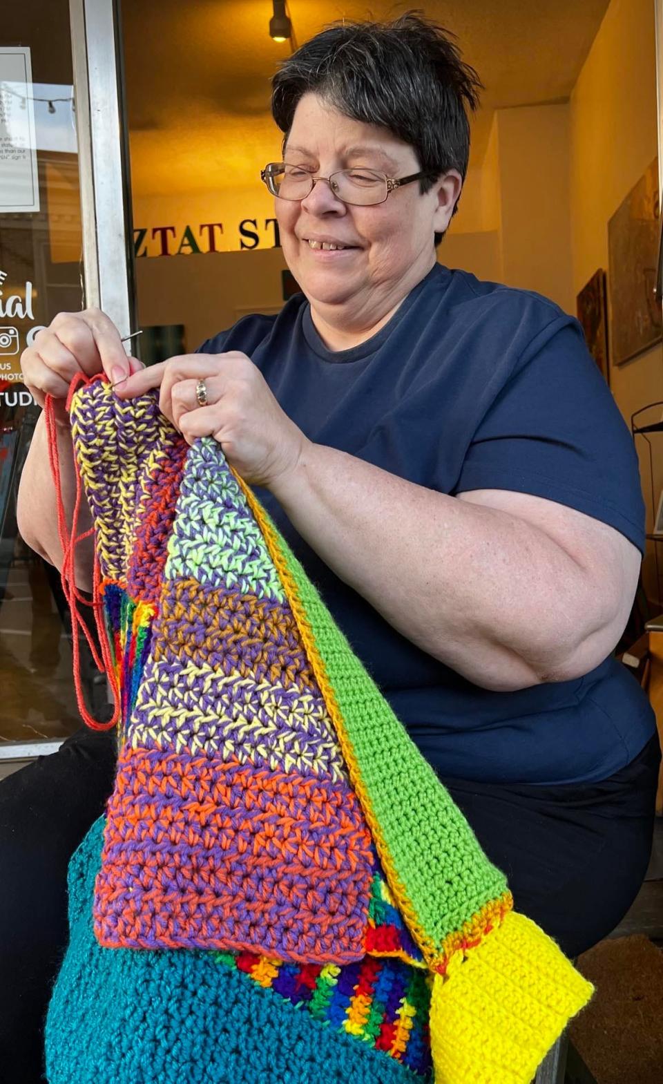 Volunteer Barb Resch works on yarn art on Sixth Street NW in downtown Canton. The artwork will be on display on poles and buildings starting Friday until September.