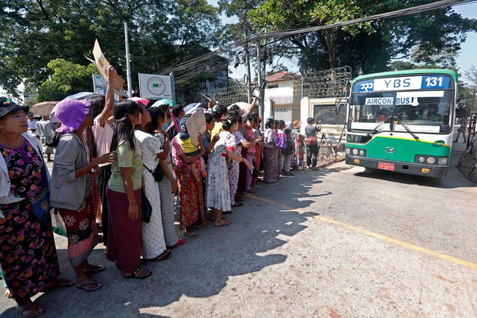 A bus carrying prisoners exits Insein prison as gathered relatives and friends await (EPA)