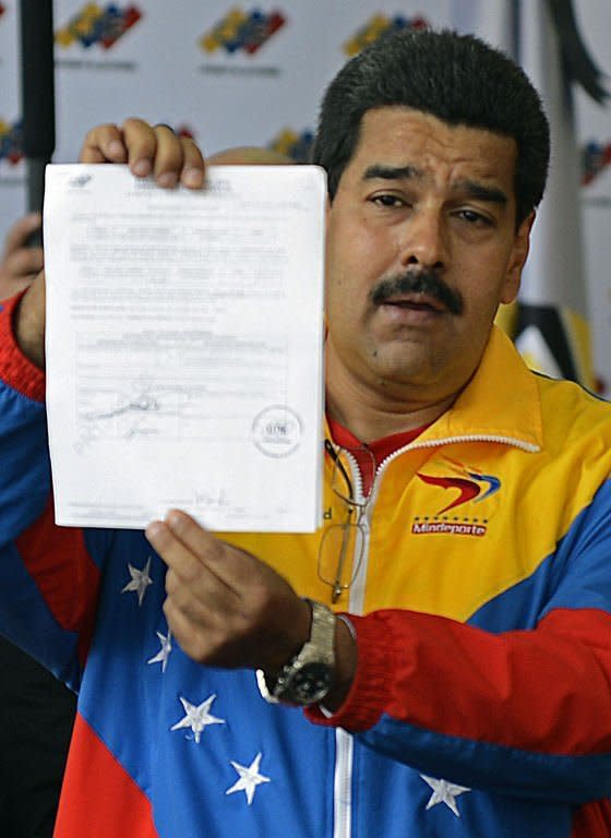 Venezuelan acting President Nicolas Maduro shows the documents from his official registration as candidate for the upcoming presidential election at the National Electoral Council in Caracas, on March 11, 2013. The campaign to succeed the late Hugo Chavez in Venezuela has officially begun and so has the mudslinging, good and thick