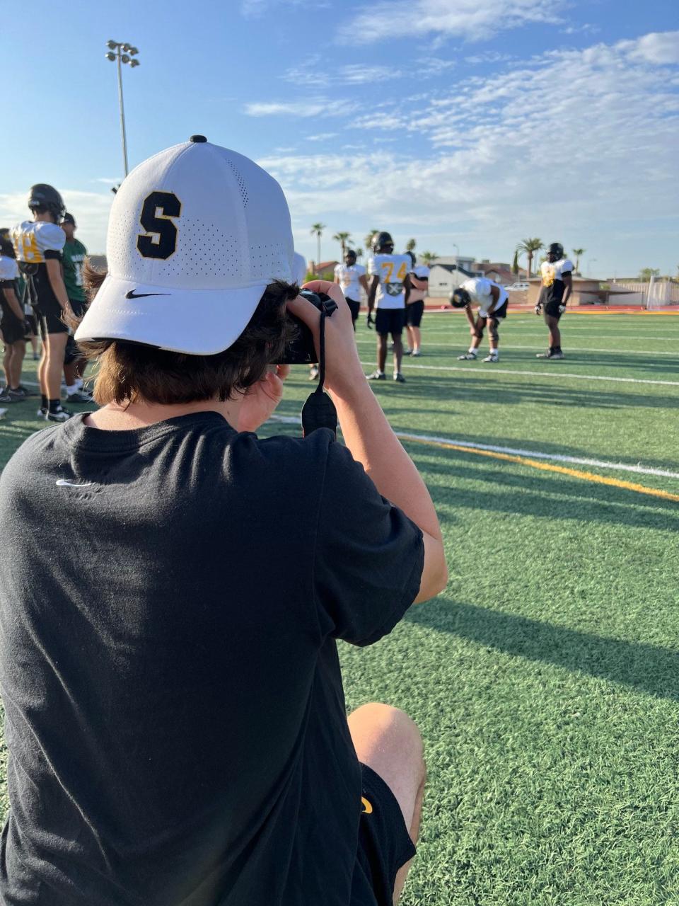 Cole Topham, in his role as creative director, takes photos at a recent football practice at Saguaro High School in Scottsdale, Ariz.