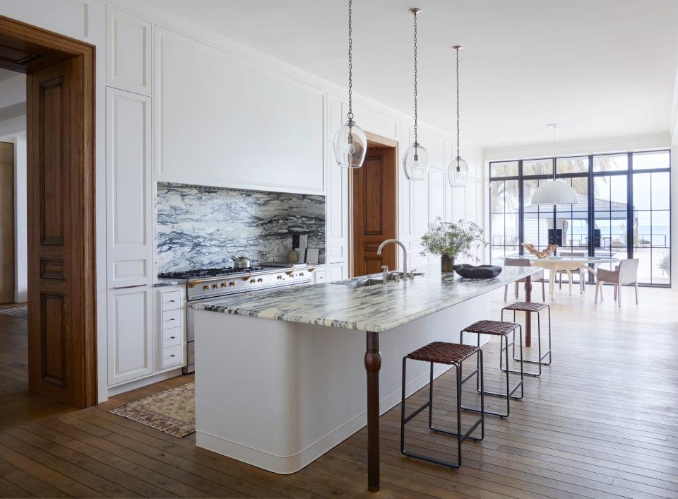 “The goal here was to create a beautifully paneled room first and a functional kitchen second,” says Mann of the sophisticated kitchen space. Paonazzo marble on the countertop and backsplash add drama, while leather-clad stools by Mark Albrecht impart warmth. The pendants are by Rose Uniacke.