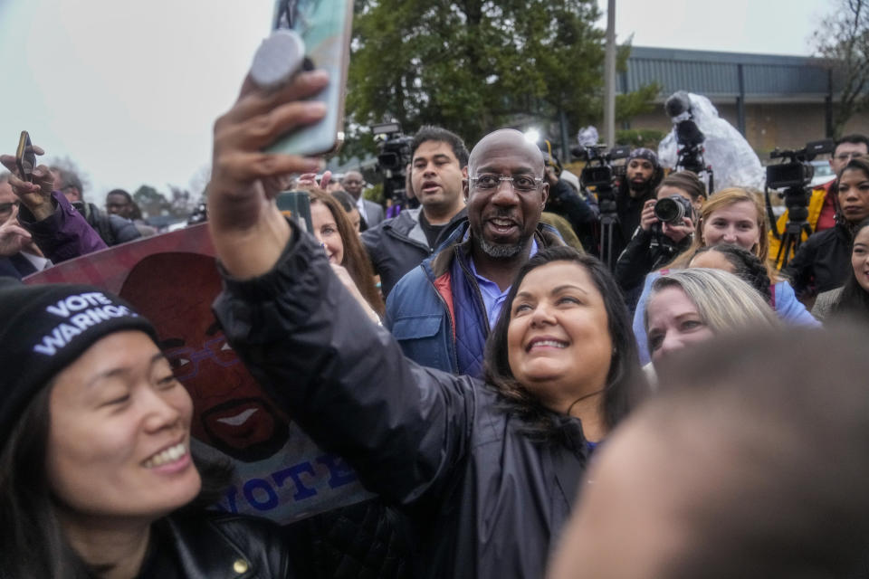 Democratic Sen. Raphael Warnock poses with supporters during an election day canvass launch on Tuesday, Dec. 6, 2022, in Norcross, Ga. Sen. Warnock is running against Republican candidate Herschel Walker in a runoff election. (AP Photo/Brynn Anderson)