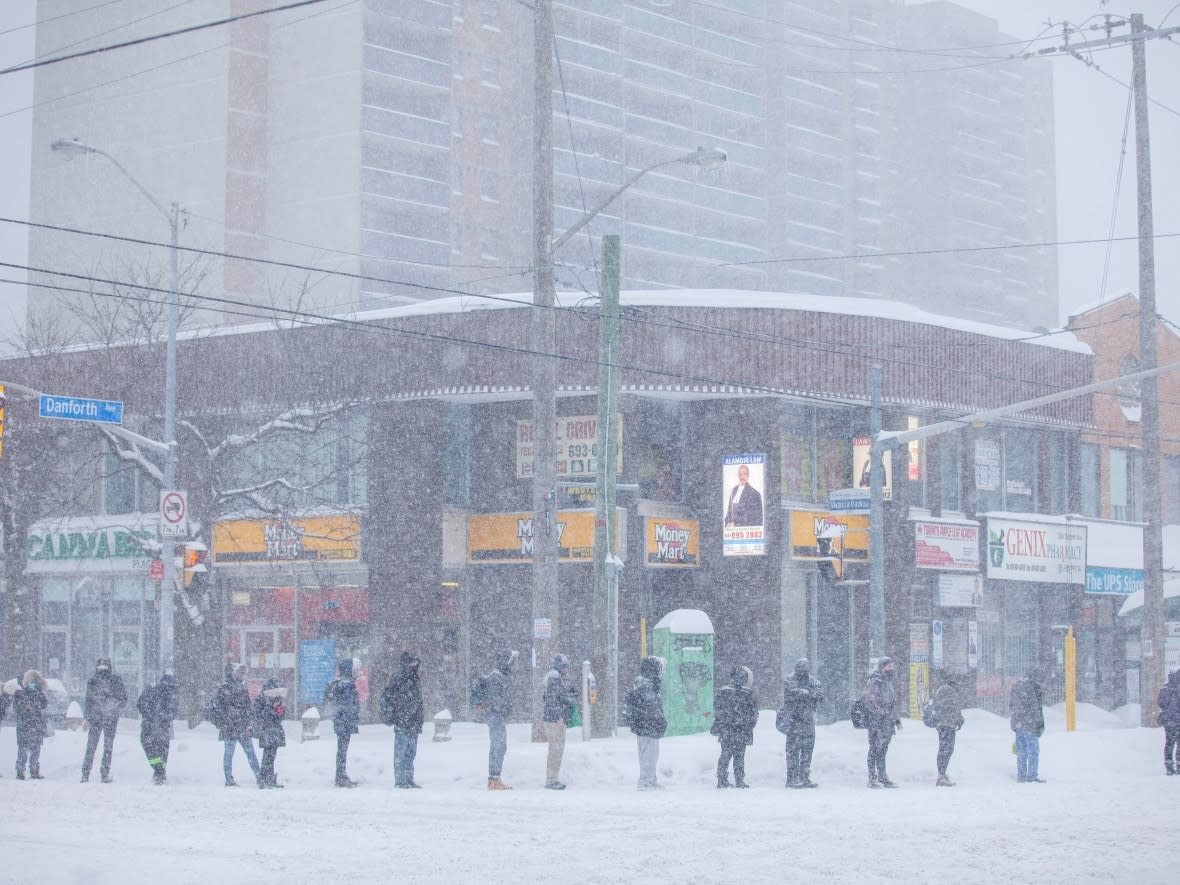 People wait at TTC bus stop at Victoria Park and Danforth avenues in Toronto on Jan. 17. More snow is in the forecast for Toronto Monday. (Gage Fletcher - image credit)
