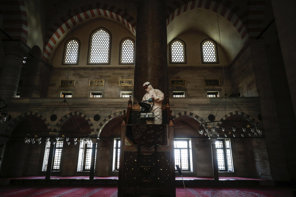 A municipality worker, wearing a protective suit against the coronavirus, disinfects the historical Suleymaniye Mosque, in Istanbul, during the third day of Eid el-Fitr and the last day of a four-day curfew due to the outbreak, Tuesday, May 26, 2020. Istanbul's municipality workers disinfected several mosques which were locked down for more than six weeks and will be partly open again for prayers on Friday, May 29. The Muslim holiday marking the end of the fasting month of Ramadan, traditionally a time of gathering, was marked by a nationwide lockdown to combat the coronavirus. (AP Photo/Emrah Gurel)